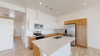 Located at 5602 Shadow Hills Rd in Las Cruces, New Mexico, this single-story, 3-bedroom, 2-bathroom home offers a thoughtfully designed layout with clean, modern finishes. Light-toned wood-look tile flooring runs throughout the home, complementing the crisp white walls and creating a bright, cohesive aesthetic.

The open-concept living, dining, and kitchen area serves as the heart of the home. The kitchen is highlighted by a large central island with a quartz countertop and undermount sink, two-tone cabinetry featuring white upper cabinets and warm natural wood lower cabinets, and a full suite of stainless steel appliances. Soaring ceilings above the kitchen add an impressive sense of volume and openness.

The living area benefits from recessed lighting, multiple windows, and access to an outdoor balcony, inviting natural light and views of the surrounding landscape. A wide hallway connects the bedrooms, each featuring neutral walls, wood-look tile floors, and ample natural light. The spacious primary bedroom includes a generous walk-in closet with built-in shelving. Two full bathrooms are finished with quartz vanity countertops, warm wood cabinetry, rectangular undermount sinks, and brushed nickel fixtures; one features a tub-shower combo. A dedicated laundry room and three closets round out this well-appointed home.