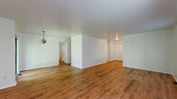 Located at 3140 State Route 209 in Kingston, NY, this single-floor, 3-bedroom, 2-bathroom home offers a practical and comfortable layout with consistent warm-toned hardwood-style flooring flowing throughout every room. The open living room is bright and generously sized, with multiple windows that invite natural light and offer views of the surrounding greenery. The kitchen features rich wood cabinetry, white countertops, a gas range, and a full-size refrigerator, with a layout that connects efficiently to the living area. The spacious primary bedroom provides ample room for furnishings and includes a large double closet, with a bathroom conveniently accessible nearby. Two additional bedrooms offer flexibility, each with hardwood-style flooring; one features track lighting and a window overlooking lush trees. The two bathrooms include a standalone shower stall and a full tub-shower combo, both finished in clean white. A dedicated laundry room houses a full-size washer and dryer alongside a water heater, adding everyday convenience. Clean white walls and neutral finishes throughout give the home a fresh, move-in-ready feel well-suited for a variety of lifestyles.