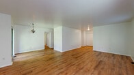 Located at 3140 State Route 209 in Kingston, NY, this single-floor, 3-bedroom, 2-bathroom home offers a practical and comfortable layout with consistent warm-toned hardwood-style flooring flowing throughout every room. The open living room is bright and generously sized, with multiple windows that invite natural light and offer views of the surrounding greenery. The kitchen features rich wood cabinetry, white countertops, a gas range, and a full-size refrigerator, with a layout that connects efficiently to the living area. The spacious primary bedroom provides ample room for furnishings and includes a large double closet, with a bathroom conveniently accessible nearby. Two additional bedrooms offer flexibility, each with hardwood-style flooring; one features track lighting and a window overlooking lush trees. The two bathrooms include a standalone shower stall and a full tub-shower combo, both finished in clean white. A dedicated laundry room houses a full-size washer and dryer alongside a water heater, adding everyday convenience. Clean white walls and neutral finishes throughout give the home a fresh, move-in-ready feel well-suited for a variety of lifestyles.