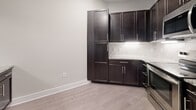 This well-appointed 680-square-foot, one-bedroom, one-bathroom apartment at 13504 Citicards Way in Jacksonville, FL offers a thoughtfully designed single-floor layout. The open-concept kitchen and living area is anchored by rich dark cabinetry with sleek hardware, granite countertops, a marble-style tile backsplash, and stainless steel appliances. Light wood-style flooring runs throughout the main living space, complemented by neutral-toned walls and ceiling fans that enhance airflow and comfort. French doors in the living room flood the space with natural light and provide outdoor access. The 170-square-foot bedroom features plush carpeting, a ceiling fan with light fixture, and windows that bring in additional natural light. The bedroom connects directly to a spacious walk-in closet outfitted with multi-tier wire shelving for ample storage. The full bathroom includes a dark-vanity with granite countertop, a tub/shower combination with marble-style surround tile, and wood-look flooring. A dedicated in-unit laundry room accommodates a full-size washer and dryer side by side, adding everyday convenience to this efficient and modern apartment.