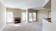 Located at 16650 Huebner Rd in San Antonio, TX, this single-floor residence offers a thoughtfully designed layout with comfortable living spaces throughout. The expansive living room serves as the heart of the home, featuring warm neutral-toned carpeting, crisp crown molding, and a tile-surround fireplace flanked by large windows that invite generous natural light. French doors open directly to an outdoor area, blending indoor and outdoor living seamlessly. The open layout extends into a secondary living or dining area, defined by a curved half-wall that connects to the kitchen. The kitchen is well-equipped with rich dark wood cabinetry, granite countertops, stainless steel appliances including an electric range and over-the-range microwave, and light hardwood flooring that adds warmth to the space. A hallway leads to the private areas of the residence, including a full bathroom finished with tile-accented tub and shower surround, dark granite vanity countertop, dark wood cabinetry, and hardwood flooring. Throughout the residence, neutral warm beige tones, crown molding details, and abundant window coverage create a bright, cohesive, and welcoming atmosphere ideal for comfortable everyday living.