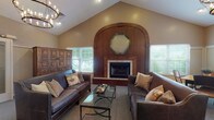 Located at 4320 Mannington Blvd in Stow, Ohio, this single-floor community space is thoughtfully designed to accommodate a variety of social functions and gatherings. The centerpiece of the space is a sophisticated lounge area with soaring vaulted ceilings, anchored by a striking wood-paneled fireplace wall featuring an arched surround and an octagonal decorative mirror. Leather sofas with nailhead trim are arranged around a glass-top coffee table, creating a warm and inviting seating area. An elegant wrought-iron candelabra chandelier adds a refined touch overhead, complementing the rich, earthy tones throughout.

Adjacent to the lounge is a more casual seating area that opens toward a pass-through window connecting to the kitchen, allowing for easy service during events. The galley-style kitchen is fully equipped with ample cabinetry, tile flooring, black appliances including a refrigerator, microwave, and dishwasher, along with generous counter space for food preparation.

A separate dining area accommodates multiple tables and chairs, bathed in natural light from large windows and French doors that open to an outdoor area. The space benefits from a cohesive, neutral color palette with warm beige walls, carpeted floors in the common areas, and consistent architectural detailing throughout, making it a versatile and welcoming venue.