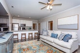 This single-story home on Front Porch Ct in Midland City, Alabama offers a thoughtfully designed open-concept layout that connects the living, dining, and kitchen areas into one cohesive space. Crown molding and recessed lighting are consistent throughout, lending a clean, polished aesthetic to the neutral-toned interiors.

The living area is generously proportioned, featuring dark hardwood-style flooring, large windows that admit ample natural light, and a ceiling fan overhead. It flows seamlessly into the kitchen, which is outfitted with white shaker-style cabinetry, granite countertops, stainless steel appliances, and a breakfast bar with seating — ideal for casual dining.

The bedrooms are carpeted and well-lit, each with windows providing views of the surrounding neighborhood. The primary bedroom is notably spacious, accommodating a sitting area alongside bedroom furnishings.

Both bathrooms share a consistent design language: white vanity cabinetry, granite countertops, framed mirrors, tile flooring, and shower/tub combinations. A dedicated laundry room houses a full-size washer and dryer with overhead shelving for storage. The home's cohesive finishes and functional layout make it a practical and comfortable residence.