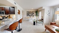 Located on Caravel Dr in Oklahoma City, OK, this single-floor residence offers a thoughtfully designed layout with 1 bedroom and 2 full bathrooms. The open-concept living and dining area is bright and welcoming, featuring plush carpeting, white walls, and an abundance of natural light from large windows dressed with grid-pattern curtains. The living room provides a comfortable, airy feel, while the adjoining dining area includes a defined space ideal for entertaining. The kitchen features light wood-tone flooring, marble-look countertops, rich dark wood cabinetry, and stainless steel appliances, including a full-size refrigerator. A breakfast bar with bar seating adds convenience and style. The spacious primary bedroom includes a ceiling fan, generous wall space, carpeted flooring, and a window with exterior views. Both bathrooms are well-appointed with dark wood vanity cabinetry, marble-look countertops, tiled tub-shower combos, and light wood-tone flooring. One bathroom also features a built-in closet with shelving and washer/dryer connections. Throughout the space, a cohesive mid-century modern design aesthetic ties each room together with warm wood tones and clean, neutral finishes.