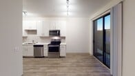 Located at 151 E Blount Ave in Knoxville, Tennessee, this single-floor unit offers a well-designed layout with a clean, contemporary aesthetic throughout. The open-concept kitchen is a standout feature, equipped with stainless steel appliances including a range, microwave, and dishwasher, complemented by crisp white cabinetry, light countertops, and a subway tile backsplash. Track lighting illuminates the space, and a sliding glass door leads directly to a private balcony, bringing in natural light and outdoor views. The living and bedroom areas feature warm hardwood-style flooring, while the bedroom is finished with plush carpeting and includes a ceiling fan with light fixture. Multiple doors in the bedroom provide access to a walk-in closet, an in-unit laundry area, a bathroom, and the adjoining kitchen. The bathroom is appointed with classic white subway tile surrounding a full soaking tub and shower, lending a timeless, clean look. Throughout the unit, neutral tones, consistent trim work, and ceiling fans contribute to a comfortable and functional living environment suited for everyday living.