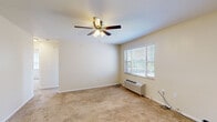 This efficiently designed 3-bedroom, 1-bathroom unit is laid out entirely on a single floor, making it easy to navigate. The bedrooms are carpeted throughout and feature ceiling fans with light fixtures, wall-mounted HVAC units, and blinds-covered windows that allow natural light to filter in. The spacious primary bedroom benefits from dual windows offering outdoor views, while the additional bedrooms include closets with built-in shelving and hanging rods for practical storage. The kitchen is outfitted with warm-toned wood cabinetry, granite countertops, tile flooring, and stainless steel appliances including a refrigerator and dishwasher. A dedicated dining room adjoins the kitchen area, providing a defined space for meals. The bathroom is a standout feature, showcasing full stone-look tile wall surrounds, a soaking tub, a built-in niche for storage, and a glass block window that introduces natural light while maintaining privacy. Throughout the unit, neutral beige walls and light-toned finishes create a clean, cohesive aesthetic. The overall layout is functional and straightforward, offering a comfortable living environment with practical amenities across every room.