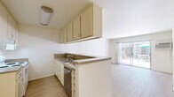 Located at 3415 Linden Ave in Long Beach, California, this one-bedroom, one-bathroom residence offers a clean, functional layout across a single floor. Light wood flooring runs throughout the entire unit, creating a bright and cohesive aesthetic. The open living area is bathed in natural light and features sliding glass doors that open directly to a shared outdoor courtyard, complete with patio seating and a relaxing California atmosphere. A wall-mounted air conditioning unit ensures year-round comfort. The galley-style kitchen is efficiently designed with cream cabinetry lining both walls, stone-look countertops, a stainless steel dishwasher, and a white range — providing ample storage and workspace. Upper cabinets extend to the ceiling for added capacity, and a pass-through peninsula connects the kitchen to the living area. The spacious bedroom features a gold-framed mirrored sliding closet door, a ceiling fan with light fixture, and a large window that invites natural light and outdoor views. An additional mirrored door adds depth to the room. The bathroom is finished with light wood-tone flooring, a combination tub-shower with a glass sliding door, a vanity with storage, and accessibility grab bars, reflecting a practical and thoughtful design.