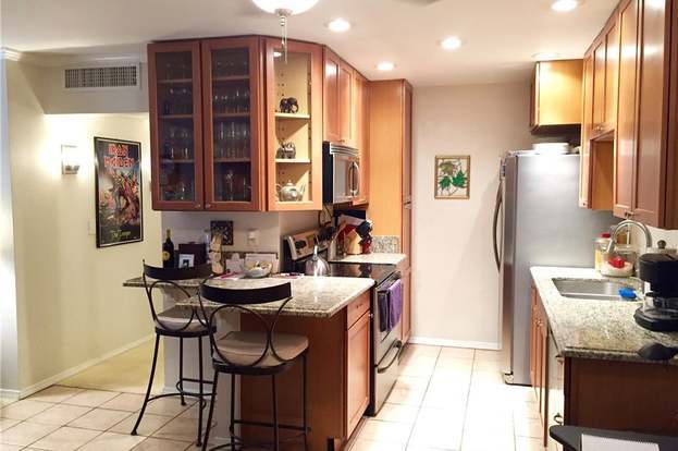 Cocina remodelada con encimeras de granito extendidas y armarios. - 436 N Bellflower Blvd