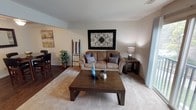 This single-floor residence offers a thoughtfully designed layout across several distinct living spaces. The living room serves as the heart of the home, featuring warm neutral tones, carpet over hardwood flooring, and a large sliding glass door that opens to a private balcony with outdoor views, allowing natural light to fill the space. A decorative wrought-iron wall piece adds character above the comfortable sofa seating arrangement.

The kitchen is well-equipped with rich dark wood cabinetry, dark granite-style countertops, a gas range, stainless steel dishwasher, and hardwood floors — providing both style and functionality. Adjacent to the kitchen, a cozy dining area accommodates a round wooden table beneath a ceiling light fixture, accented by coordinating wall art.

The primary bedroom offers plush carpeting and ample space, complemented by a large dark-wood dresser with mirror and convenient access to a hallway. The second bedroom, also carpeted, provides a comfortable and versatile space suitable for guests or a home office. The full bathroom features tile flooring, a shower-tub combination, and a vanity with dark wood cabinetry, offering a clean and practical design. Together, these spaces create a cohesive and comfortable living environment.