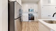 Located at 104 Herrings Green Loop in Mooresville, NC, this single-story, one-bedroom, one-bathroom home offers a thoughtfully designed layout that maximizes every square foot. The open-concept kitchen and living area serves as the heart of the home, featuring light wood-tone flooring, white shaker cabinetry, a subway tile backsplash, and a full suite of stainless steel appliances including a refrigerator, range, and microwave. A central island with a white quartz countertop, undermount sink, and pendant lighting adds both function and style, complemented by matte black hardware throughout. The living area receives ample natural light through large windows and a glass-paneled door that opens to the outdoors. The bedroom is comfortably sized, finished with plush carpet, a ceiling fan, and a window with outdoor views. A dedicated walk-in closet with wire shelving provides generous storage. The full bathroom is appointed with a white vanity, quartz countertop, tub-shower combination with tiled surround, and wood-look flooring. Clean neutral tones, consistent finishes, and an efficient floor plan give this home a cohesive, modern feel throughout.