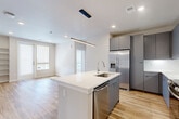 Located at 15075 Belford Ave in Parker, CO, this well-appointed 2-bedroom, 2-bathroom home offers a thoughtfully designed single-floor layout with modern finishes throughout. Light wood-look flooring flows seamlessly across the entire residence, creating a cohesive and airy aesthetic.

The open-concept kitchen and living area serves as the heart of the home. The kitchen is equipped with sleek gray flat-front cabinetry extending to the ceiling, stainless steel appliances including a French door refrigerator, electric range, microwave, and dishwasher, all complemented by white quartz countertops and a subway tile backsplash. A kitchen island with a single-basin sink and pendant lighting adds both function and style, with the living area opening naturally beyond it.

A convenient mudroom entry features built-in wall hooks and a bench, providing an organized drop zone. Both bedrooms are bright and sun-filled, benefiting from multiple windows with roller shades and a ceiling fan in the primary. One bedroom includes a sliding glass door leading to a private balcony and built-in shelving. Each bedroom is served by its own closet, including a walk-in. The bathrooms feature wood-look tile flooring, and one includes a tub and shower surround clad in large-format marble-style tile with open shelving nearby.