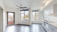 Located in Portland's vibrant NE neighborhood at 2180 NE 47th Ave, this efficiently designed one-bedroom, one-bathroom unit offers a modern and functional layout across a single floor. The open-concept living, dining, and kitchen area serves as the heart of the home, featuring light gray hardwood-style flooring, crisp white walls, and a ceiling fan that anchors the space. Large windows with roller shades flood the room with natural light while framing views of the surrounding neighborhood, and a private balcony provides an outdoor retreat accessible from the main living area. The kitchen is outfitted with gray cabinetry, open shelving, a countertop sink, built-in microwave, and a full-size refrigerator, all illuminated by recessed lighting. The bedroom is a comfortable, well-lit space with its own large window offering additional neighborhood views and the same warm flooring carried throughout. The bathroom features a clean, minimalist design with a white vanity, integrated sink, wall mirror, chrome fixtures, and a walk-in shower. Every detail reflects a contemporary aesthetic with a neutral palette, making this unit a polished and practical home in the heart of Portland.
