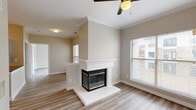This single-floor residence offers a clean, modern aesthetic carried consistently throughout its thoughtfully designed layout. The living area serves as a focal point of the home, anchored by a striking double-sided fireplace framed in crisp white with elegant crown molding detail above. A ceiling fan overhead and natural light streaming through slatted blinds contribute to a bright, comfortable atmosphere. Wood-look plank flooring extends seamlessly across all areas of the home, providing both warmth and visual continuity.

The kitchen is well-equipped and stylish, featuring white shaker-style cabinetry with brushed nickel hardware, a classic subway tile backsplash, dark countertops, a stainless steel undermount sink, and stainless steel appliances. The cabinetry extends to the ceiling, maximizing storage capacity.

A spacious bedroom benefits from dual windows that invite abundant natural light, with a ceiling fan providing additional comfort. The neutral wall tones and wide-plank flooring give the room a calm, airy feel.

The bathroom is functional and straightforward, offering a vanity with an illuminated mirror, a full-size soaking tub with tiled surround, and rich, darker wood-look flooring that adds warmth to the space. Overall, the home presents a cohesive and move-in ready interior with modern finishes throughout.