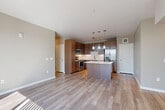 Located in Denver's Green Valley Ranch neighborhood, this well-designed two-bedroom, two-bathroom residence offers a thoughtful single-level floor plan with a balanced mix of comfort and modern style. The open-concept living, dining, and kitchen area forms the heart of the home, bathed in natural light from large sliding glass doors that lead to a private balcony overlooking the surrounding community. Light wood-style flooring flows throughout the main living areas, creating a clean, cohesive aesthetic. The kitchen is a standout feature, equipped with stainless steel appliances including a refrigerator, range, and microwave, complemented by warm wood-toned cabinetry, white quartz countertops, a patterned tile backsplash, a center island, and pendant lighting. A dedicated pantry provides additional storage convenience. Both bedrooms are carpeted for comfort; the primary bedroom offers a generous footprint with balcony access, while the second bedroom features dual windows that bring in ample natural light. The bathrooms are finished with wood-grain vanity cabinetry and white quartz countertops, with one featuring a full tub-shower combination and tile surround. Three closets, including a walk-in with wire shelving, a laundry area, utility room, bonus room, and hallway complete this well-appointed residence.