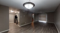 This single-floor residence offers a thoughtfully designed layout that balances comfort and functionality throughout its living spaces. The open living and dining area is anchored by rich, dark hardwood-style flooring and neutral taupe-toned walls, creating a warm and cohesive aesthetic. A stylish pendant light fixture serves as a focal point overhead, while large vertical blinds allow natural light to filter into the space. The kitchen is well-equipped and features granite countertops with subtle veining, gray cabinetry, a classic white subway tile backsplash, a stainless steel double-basin sink, a dishwasher, and a full-size refrigerator. A window above the sink brings in additional natural light. The bedroom is finished with soft wall-to-wall carpeting, deeper gray walls, a ceiling fan with light fixture, and a window dressed with horizontal blinds. The bathroom includes a granite-topped vanity with gray cabinetry, a full tub-shower combination with white tile surround, and wood-look flooring that ties back to the rest of the unit. Overall, the space presents a clean, modern, and move-in-ready environment with consistent finishes throughout.
