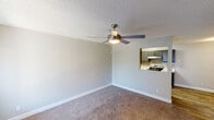 Located at 40 E Sunland Ave in Phoenix, AZ, this single-floor residence offers a functional and well-organized layout across several distinct living areas. The living room is a comfortable, open space finished with plush wall-to-wall carpeting, neutral gray walls, and a textured ceiling. A modern ceiling fan with an integrated light fixture anchors the room, while a convenient pass-through window connects directly to the kitchen, enhancing the open feel between the two spaces. The kitchen is thoughtfully designed with gray cabinetry, white countertops, and a subway tile backsplash. Stainless steel appliances, including a refrigerator and an electric range, complement the light wood-look vinyl plank flooring, giving the space a clean, contemporary aesthetic. The bedrooms are well-proportioned, each featuring soft carpeting, textured ceilings, and windows fitted with vertical blinds that allow for natural light and privacy. At least one bedroom includes a built-in closet with a rod and shelf, providing practical storage. The consistent use of neutral tones throughout the space — warm whites, soft beiges, and cool grays — creates a cohesive and inviting atmosphere. The straightforward single-floor layout offers ease of movement and accessibility throughout.
