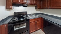 Located at 209 W Lockhaven Dr in Goldsboro, NC, this single-floor unit offers a practical and comfortable layout designed for everyday living. Throughout the space, wood-look luxury vinyl flooring provides a consistent, clean aesthetic, complemented by neutral-toned walls and textured ceilings.

The open living area is generously sized, featuring a ceiling fan with light fixture and a sliding glass door that opens to a private balcony, allowing natural light to pour in and providing outdoor views. An electrical panel is conveniently accessible within the living space. The area flows naturally toward the kitchen, which is equipped with rich cherry-toned cabinetry, dark granite-style countertops, a black electric range with overhead exhaust, a stainless steel sink, and a dishwasher — offering ample storage and workspace.

The bedrooms are well-proportioned, each featuring wood-look flooring, neutral walls, and windows fitted with blinds that bring in natural light. One bedroom includes a closet with a six-panel door. The bathroom features a full tub/shower combination with grab bar, a toilet, wood-look flooring, and a vanity with matching cherry-toned cabinetry, maintaining a cohesive style throughout the unit.