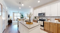 Located along Stone Mountain Highway in Stone Mountain, GA, this well-designed one-bedroom, one-bathroom residence offers a thoughtfully organized single-floor layout that maximizes every square foot. The open-concept kitchen and living area serves as the heart of the home, where a granite-topped island with pendant lighting above creates an inviting focal point. The kitchen features a two-tone cabinet design — crisp white upper cabinets paired with warm wood lower cabinets — accented by a classic subway tile backsplash and stainless steel appliances, including a range, microwave, and refrigerator. Wood-style flooring flows throughout the main living areas, contributing to a warm, cohesive aesthetic. The living room is bright and airy, benefiting from large windows that draw in generous natural light and offer exterior views. The bedroom is a comfortable retreat, carpeted underfoot, with a large window that fills the space with daylight. The bathroom is clean and functional, featuring granite countertops, wood-toned cabinetry, and direct access to a dedicated walk-in closet with built-in shelving. A hallway connects the spaces efficiently, completing this smartly designed residence with a modern, neutral palette throughout.