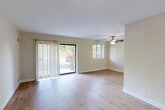 Located at 5902 31st Ave in Hyattsville, MD, this one-bedroom, one-bathroom residence offers a well-organized, single-floor layout designed for comfortable everyday living. The spacious living room is a standout feature, bathed in natural light through a large sliding glass door with vertical blinds that opens to an outdoor view of lush greenery, complemented by an additional window and a ceiling fan overhead. Light-toned hardwood-style flooring flows consistently throughout the living areas and bedroom, creating a cohesive and airy feel. The galley-style kitchen is efficiently designed with warm honey-toned wood cabinetry, stone-patterned countertops, a mosaic tile backsplash, white appliances including a gas range and refrigerator, a stainless steel sink, and dark marble-style flooring. The bedroom is well-proportioned and bright, featuring a wide window with natural light and two sets of bifold closet doors that provide generous storage with built-in shelving and hanging rods. The full bathroom is clean and functional, featuring white tile surround, a tub-shower combination, a vanity with medicine cabinet mirror, and under-sink cabinetry. A hallway connects the main spaces seamlessly, rounding out a practical and inviting layout.
