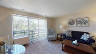 Located at 111 Grafton Ave in Dayton, Ohio, this single-floor residence offers a well-organized and functional layout designed for comfortable everyday living. The living room serves as the heart of the home, featuring plush wall-to-wall carpeting, neutral-toned walls, and a large sliding glass door fitted with vertical blinds that opens to a private balcony. The balcony provides pleasant outdoor views of the surrounding greenery, allowing natural light to fill the space throughout the day. The living area offers ample room for seating arrangements and casual entertaining. Adjacent to the living space, the kitchen is equipped with white cabinetry offering generous storage, a gas range with overhead ventilation, a double-basin sink, and dark-toned countertops that contrast cleanly with the bright cabinetry. The flooring transitions to a durable tile-style surface, practical for a cooking environment. The bedroom is a calm and restful retreat, carpeted for warmth and comfort, with a window that brings in soft natural light. A hallway connects the main living areas to the bathroom, which features white fixtures, a vanity with a medicine cabinet, and tile flooring. Built-in storage and closet space are accessible along the hallway, adding to the unit's overall practicality. The layout flows efficiently, making thoughtful use of every area throughout the home.