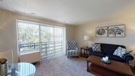 Located at 111 Grafton Ave in Dayton, Ohio, this single-floor residence offers a well-organized and functional layout designed for comfortable everyday living. The living room serves as the heart of the home, featuring plush wall-to-wall carpeting, neutral-toned walls, and a large sliding glass door fitted with vertical blinds that opens to a private balcony. The balcony provides pleasant outdoor views of the surrounding greenery, allowing natural light to fill the space throughout the day. The living area offers ample room for seating arrangements and casual entertaining. Adjacent to the living space, the kitchen is equipped with white cabinetry offering generous storage, a gas range with overhead ventilation, a double-basin sink, and dark-toned countertops that contrast cleanly with the bright cabinetry. The flooring transitions to a durable tile-style surface, practical for a cooking environment. The bedroom is a calm and restful retreat, carpeted for warmth and comfort, with a window that brings in soft natural light. A hallway connects the main living areas to the bathroom, which features white fixtures, a vanity with a medicine cabinet, and tile flooring. Built-in storage and closet space are accessible along the hallway, adding to the unit's overall practicality. The layout flows efficiently, making thoughtful use of every area throughout the home.