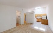 This single-story space is thoughtfully laid out, offering a comfortable and functional living environment throughout. The main living area is a standout feature, showcasing soaring vaulted ceilings accented by a skylight that floods the room with natural light. Neutral-toned carpet extends across this space, contributing to a warm and inviting atmosphere, while the open sightlines connect seamlessly to the adjacent kitchen.

The kitchen is well-equipped with honey-toned wood cabinetry extending to the upper walls, dark granite-style countertops, and a full suite of white appliances including a refrigerator, electric range, dishwasher, and washer and dryer. Light wood-style flooring runs throughout the kitchen, providing a clean contrast to the carpeted living spaces.

The bedroom is generously sized with plush carpeting and features access to a dedicated walk-in closet with built-in shelving, offering ample storage. An additional door within the bedroom provides further utility access.

The bathroom is neatly appointed with a wood-framed vanity, white countertop, a large framed mirror with overhead lighting, and a tub-shower combination, all finished with light tile flooring. Overall, the space maintains a clean, neutral palette throughout.