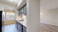 This single-story unit offers four bedrooms and two full bathrooms within a well-designed, efficiently laid-out floor plan. The kitchen is a functional galley-style space featuring dark navy cabinetry with modern hardware, light quartz countertops, a classic subway tile backsplash, a double-basin stainless steel sink, and stainless steel appliances, including a refrigerator. Wood-style laminate flooring runs throughout, tying each room together cohesively. The living room is a bright, open space highlighted by a ceiling fan with light fixture and neutral-toned walls that create a clean, welcoming atmosphere. Each bedroom is comfortably sized, with the primary bedroom offering direct access to a closet and an en-suite bathroom. Ceiling fans are present in multiple bedrooms, promoting air circulation and comfort. The two bathrooms are outfitted with quartz-topped vanities — one with dark cabinetry and one with blue cabinetry — full-size soaking tubs, and shower combinations. Textured ceilings are consistent throughout the unit. An enclosed outdoor area with a horizontal wood-slat privacy fence provides a private exterior space. Two dedicated closets offer additional storage solutions within the home.