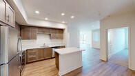 Located at 2640 Wagon Wheel Rd in Oxnard, California, this single-floor unit offers a clean, contemporary design with a thoughtfully planned layout. The open-concept kitchen serves as a central highlight, featuring warm-toned wood cabinetry extending to the ceiling, white quartz countertops, a central island ideal for dining or meal prep, and a full suite of stainless steel appliances including a refrigerator, range, microwave, and dishwasher. Recessed lighting illuminates the space efficiently throughout.

Light wood-style flooring flows seamlessly through the kitchen, living, and common areas, creating a cohesive and modern aesthetic. The living area is generously proportioned with neutral white walls and access to natural light through sliding glass doors and windows fitted with blinds.

The bedrooms are carpeted in a neutral tone, providing comfort underfoot, and each features windows that allow natural light and outdoor views of the surrounding Oxnard neighborhood. The bathrooms are finished consistently with wood-tone vanity cabinetry, white countertops, and tub-shower combinations with clean tile surrounds. Light wood flooring continues into the bathrooms, reinforcing the unit's unified design throughout.