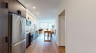 Located at 549 S Harvard Blvd in Los Angeles, this two-bedroom, one-bathroom unit offers a well-designed single-floor layout with modern finishes throughout. The open-concept kitchen is outfitted with two-tone cabinetry — white uppers paired with dark wood lowers — complemented by white quartz countertops, a tile backsplash, stainless steel appliances, and a kitchen island with bar seating, making it both functional and stylish. The kitchen flows naturally into the living room, which is filled with natural light from large windows overlooking the surrounding cityscape. Light wood-tone flooring runs throughout the main living areas, adding warmth to the neutral palette. The primary bedroom features a window with city views and wood flooring, while the second bedroom includes a sliding closet and similarly clean, bright finishes. Both rooms offer comfortable proportions and a calm, restful atmosphere. The bathroom is finished with large-format white wall tiles, stone-look floor tiling, and a full soaking tub with an overhead shower. Clean lines, recessed lighting, and a consistent modern aesthetic unify the space, creating a cohesive and livable home in the heart of Los Angeles.