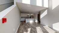 Located at 3926 S Lake Dr in St. Francis, Wisconsin, this contemporary two-story home offers a thoughtfully designed layout with modern finishes throughout. The main level features an open-concept living and kitchen area anchored by wide-plank wood-look flooring that extends throughout the space. The kitchen is a standout, showcasing crisp white shaker cabinetry, dark granite countertops, a large center island with seating, stainless steel appliances including a refrigerator, range, and microwave, and stylish pendant lighting overhead. Tall ceilings on the main level enhance the sense of openness, with natural light streaming in through multiple windows. A staircase leads to the upper level, where carpeted bedrooms offer a comfortable retreat. Bedrooms feature large windows with neighborhood views and ample natural light. A spacious walk-in closet with wire shelving provides generous storage. The bathrooms are finished with white vanity cabinetry, granite-style countertops, and combination tub/shower units. A carpeted upper hallway connects the bedrooms and provides convenient access to the laundry area and additional storage. The overall aesthetic is clean, bright, and move-in ready, reflecting a cohesive modern design throughout both floors.