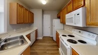Located at 111 Northwynd Cir in Lynchburg, Virginia, this single-floor home offers a practical and comfortable layout designed for everyday living. The kitchen is well-appointed with warm honey-toned wood cabinetry lining both walls, white appliances including a coil-burner range, built-in microwave, dishwasher, and refrigerator, all complemented by durable hardwood-style flooring and ample counter space. A pantry or utility closet is accessible from within the kitchen.

The living area is bright and open, featuring hardwood-style flooring, a ceiling fan with light fixture, neutral gray walls, and large sliding glass doors with vertical blinds that invite natural light and provide outdoor access. The bedrooms are carpeted for comfort, each equipped with ceiling fans and natural light from windows with blinds. Several bedrooms include closets with built-in shelving, offering convenient storage solutions.

Two full bathrooms serve the home, each featuring a clean, white tub-and-shower combo with chrome fixtures and neutral gray walls. One bathroom includes a safety grab bar, adding an accessibility-conscious touch. Throughout the home, consistent neutral tones, white trim, and textured ceilings create a cohesive and move-in ready aesthetic well-suited for a variety of residents.