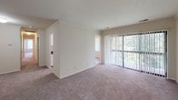 Located at 13837 Castle Blvd in Silver Spring, Maryland, Unit 42 is a single-floor residence offering a functional and comfortable layout. The open living area is generously proportioned, featuring plush wall-to-wall carpeting and a large sliding glass door with vertical blinds that allows abundant natural light and outdoor views to fill the space. The galley-style kitchen is well-appointed with white cabinetry, dark granite-style countertops, a gas range, refrigerator, and a double sink — all set atop wood-look vinyl flooring that adds a clean, modern touch. The bedrooms are carpeted and bright, each featuring windows with vertical blinds that provide views of the surrounding greenery. A standout feature of the primary bedroom is the dual walk-in closets, offering exceptional storage. The unit includes two bathrooms, each finished with dark countertops, white cabinetry, and wood-look flooring. Crown molding accents several rooms, adding a refined architectural detail throughout. The neutral color palette and consistent finishes create a cohesive, move-in-ready atmosphere throughout the entire residence.