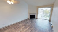 Located at 510 Stevens Ave SW, Unit N302 in Renton, Washington, this single-floor residence offers a clean, well-maintained living environment with a thoughtful layout and inviting design details. The main living area is spacious and open, featuring warm hardwood-style flooring that runs throughout, lending a cohesive and modern feel to the space. A tiled fireplace serves as a natural focal point in the living room, adding both character and a cozy ambiance. Adjacent to the fireplace, a large sliding glass door fitted with vertical blinds allows for an abundance of natural light to fill the room while providing direct access to an outdoor area, perfect for enjoying fresh air and views of the surrounding greenery. The walls are finished in a soft, neutral tone that complements the lighter flooring and creates a bright, airy atmosphere throughout. The textured ceiling adds a subtle design element consistent with the building's architectural style. Overall, this unit presents a comfortable and functional living space that balances practicality with understated style, making it a welcoming home in the Renton community.