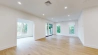 Located at 402 Halstead Ave in Harrison, NY, this thoughtfully designed single-floor residence offers a bright, contemporary living experience across two bedrooms and two bathrooms. The open-concept combined dining and living area is anchored by expansive windows and sliding glass doors that flood the space with natural light and frame lush greenery views, creating a seamless indoor-outdoor connection. Light hardwood flooring flows consistently throughout, enhancing the home's clean, modern aesthetic.

The gourmet kitchen is a standout feature, boasting high-gloss white cabinetry, a generous waterfall-edge island, stainless steel appliances including a gas range and dishwasher, a subway tile backsplash, and sleek pendant lighting. An adjacent pantry adds practical storage. The primary bedroom is generously proportioned and includes a well-appointed walk-in closet with custom built-in shelving. Additional bedrooms are bright and airy, each with large windows offering neighborhood and garden views.

Both bathrooms are finished with crisp white marble-style tile. A dedicated den, laundry room, and multiple utility and storage spaces round out the functional layout. A deck off the rear provides a peaceful outdoor retreat surrounded by mature trees.
