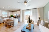 Located in Peoria, Arizona, this two-story home offers a thoughtfully designed layout spread across two floors. The ground level is anchored by an open-concept kitchen and living area that flows seamlessly together. The kitchen features crisp white cabinetry, a tile backsplash, stainless steel appliances, and a central island with bar seating — ideal for casual dining and entertaining. Light wood-tone flooring runs throughout, complementing the bright, airy atmosphere created by large windows and sliding glass doors that invite natural light. The living room is anchored by a soft sage green accent wall, ceiling fan, and direct access to an outdoor area. An attached garage with an automatic opener provides convenient enclosed parking and additional storage space. Upstairs, three bedrooms offer comfortable retreats, each with ceiling fans, ample natural light, and generous closet space. The spacious primary bedroom includes a well-appointed walk-in closet. The bathrooms are finished with clean white vanities, wood-look flooring, and a sleek glass-enclosed tiled shower. Two hallways connect the upper-level spaces efficiently. The home's neutral palette, modern fixtures, and cohesive design create a warm, inviting ambiance throughout.