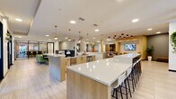 Located at 3500 Cox Rd in Henrico, Virginia, this efficiently designed single-floor unit offers a clean, contemporary aesthetic throughout. Light hardwood flooring flows seamlessly across the entire space, complemented by crisp white walls and recessed lighting that create a bright, airy atmosphere.

The galley-style kitchen is a standout feature, showcasing granite countertops, white shaker-style cabinetry with glass-front upper panels, a subway tile backsplash, and a full suite of stainless steel appliances including a range, built-in microwave, and refrigerator. A built-in counter extension provides additional workspace or casual dining space. The kitchen opens toward a living area illuminated by a large sliding glass door that frames outdoor views and floods the room with natural light. A ceiling fan adds comfort to the living area.

The bathroom is finished with large-format marble-look tile in a glass-enclosed walk-in shower with a built-in niche and brushed nickel fixtures, conveying a polished, upscale feel.

A dedicated walk-in closet features built-in shelving and hanging rods, offering well-organized storage. The overall design is modern, functional, and thoughtfully appointed throughout.