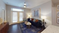 Located in Fort Mill, South Carolina, this thoughtfully designed single-floor residence offers a cohesive blend of modern functionality and bold interior style. The open-concept living area is anchored by rich hardwood-style flooring, a ceiling fan, and a set of French doors that invite natural light and provide access to an outdoor space. The kitchen is well-appointed with white shaker-style cabinetry, granite countertops, a large center island with an undermount sink, and a full suite of stainless steel appliances, making it both practical and visually striking. A dining area connects seamlessly to the kitchen and living spaces, reinforcing the open flow of the layout. The primary bedroom features a bold amber accent wall, plush carpeting, and a spacious walk-in closet with wire shelving for ample storage. Its ensuite bathroom includes a glass-enclosed walk-in shower, granite vanity, and hexagonal tile flooring. A second bedroom with a teal accent wall and natural window views offers comfortable secondary accommodations. A second bathroom with a granite vanity and hexagonal tile completes the layout. Throughout the residence, curated design touches — including statement artwork and layered lighting — create a warm, inviting ambiance.