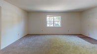 This single-floor residence offers three bedrooms and one and a half bathrooms within a practical, well-organized layout. The bedrooms are carpeted in neutral tones and feature white walls with window blinds that allow natural light to filter in. The primary bedroom includes a closet and direct access to the full bathroom, enhancing everyday convenience. The additional bedrooms share a similar design, each with windows overlooking greenery outside.

The full bathroom is equipped with a tub-shower combination featuring white tile surround, a wood-toned vanity, and hardwood-style flooring. A separate half bathroom provides a toilet and is conveniently located for guests. The kitchen is well-appointed with warm wood cabinetry, ample upper and lower storage, light hardwood-style flooring, and stainless steel appliances including a refrigerator, dishwasher, and range. A living area with carpeted flooring and a window rounds out the common spaces, creating a cohesive and functional home environment throughout.