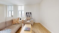 Located at 518 W Fayette St in the heart of Baltimore, MD, this 1-bedroom, 1-bathroom residence offers a thoughtfully designed single-floor layout that makes efficient use of its space. The open-concept living room and kitchen area forms the central hub of the home, bathed in natural light from large windows that offer views of the surrounding cityscape. Light wood-tone flooring runs throughout the main living areas, lending warmth and continuity to the space.

The kitchen features a galley-style layout with warm wood cabinetry, light stone countertops, and a full suite of stainless steel appliances, including a refrigerator, range, microwave, and dishwasher. The living room is generously sized with multiple windows on two walls, allowing abundant natural light and urban views to fill the room.

The spacious primary bedroom is finished with plush carpeting and benefits from corner window placement, providing natural light from multiple directions. A dedicated closet offers practical storage. The full bathroom is finished with neutral tile, a tub-shower combination, and a sleek white vanity with ample counter space and a modern mirror. A hallway connects all rooms, completing this well-organized and comfortable urban residence.