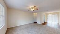 This single-story residence offers a functional and straightforward layout across several well-defined living spaces. The open living area is finished with neutral-toned carpet and features a ceiling fan with a light kit, providing both comfort and ambient lighting. A textured ceiling adds subtle architectural interest, while large windows allow natural light to filter in, creating a bright and airy atmosphere. An adjoining dining area, illuminated by a chandelier, connects seamlessly to the rest of the living space and provides access to a sliding glass door.

The galley-style kitchen is efficiently designed, featuring white cabinetry on both sides that offers generous storage space. White appliances — including a coil-top range, refrigerator, and dishwasher — are complemented by a double sink and wood-look flooring that runs the length of the kitchen.

The bedrooms are carpeted and finished in warm neutral tones, each offering closet storage with louvered bifold doors. Natural light enters through blinds-covered windows, enhancing the comfortable feel of each room.

The bathroom features a distinctive retro aesthetic, with light blue ceramic tile covering both the floor and the tub surround, paired with a white vanity and standard fixtures.