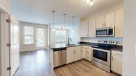 Located at 4101 Runner Lp in Chester, Virginia, this single-floor, 2-bedroom, 2-bathroom home offers a clean, modern aesthetic with thoughtful finishes throughout. The open-concept kitchen and living area serves as the heart of the home, anchored by a central island with striking granite countertops, an undermount sink with a matte black faucet, and a full suite of stainless steel appliances including a refrigerator, range, microwave, and dishwasher. Light wood-tone cabinetry with black hardware adds a contemporary touch, while pendant lighting above the island and luxury vinyl plank flooring complete the space. The living area extends naturally from the kitchen, bathed in natural light from multiple windows and sliding door access to the outdoors. Both bedrooms feature plush carpet flooring, ceiling fans, and ample natural light, with the primary bedroom offering generous proportions and dedicated closet space. The two full bathrooms are finished with granite-topped vanities and full tub-shower combinations with tiled surrounds. Neutral, warm wall tones and clean white trim flow consistently throughout the home, creating a cohesive and inviting atmosphere well-suited for comfortable everyday living.