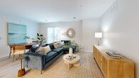 Located at 340 Driftway in Scituate, MA, this well-appointed single-floor residence offers 2 bedrooms and 3 bathrooms within a thoughtfully designed open-concept layout. Light wood-tone flooring flows throughout, unifying the living, dining, and kitchen areas into a cohesive, airy space. The kitchen is outfitted with crisp white cabinetry extending to the ceiling, stainless steel appliances, a central island with dark countertops, and recessed lighting — a functional and attractive hub for daily living. The adjoining dining area provides a welcoming setting, while the living room offers generous proportions and access to natural light through sliding glass doors. The primary bedroom is a standout retreat, featuring multiple windows, balcony access, and a walk-in closet with built-in wire shelving and hardwood flooring. The second bedroom also includes its own walk-in closet, offering excellent storage. All three bathrooms are finished with clean, modern fixtures — one includes a glass-enclosed walk-in shower with brushed gold hardware, while another features a backlit vanity mirror and white quartz countertop. The overall palette of soft whites, warm woods, and neutral tones gives the entire residence a calm, coastal ambiance befitting its Scituate location.