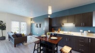 Located at 370 W Paxton Ave in Salt Lake City, Utah, this single-floor residence offers a thoughtfully designed open-concept layout that seamlessly connects the kitchen, dining, and living areas. The interior is defined by a striking teal accent wall that anchors the space and adds a bold pop of color against the neutral tones throughout.

The kitchen is well-equipped with dark espresso cabinetry, light countertops, under-cabinet lighting, and black appliances including a refrigerator and range. A freestanding dining table with bar-height stools provides a casual and functional dining solution adjacent to the kitchen.

The living area is bright and welcoming, featuring large French doors that flood the room with natural light and provide direct access to an outdoor space. Light wood-style flooring runs throughout the main living areas, complementing the contemporary aesthetic.

The entryway is clean and functional, with a teal front door that echoes the interior accent color, wall sconces for warm lighting, and smooth transitions to the main living space.

The bathroom features wood-look tile flooring, a full tub-shower combination with white tile surround, a dark vanity with a white countertop sink, and a large mirror — all contributing to a clean, modern finish.

Overall, this space offers a cohesive modern design with practical features and a warm, inviting ambiance.