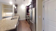 This well-appointed 2-bedroom, 2-bathroom residence is thoughtfully designed across a single floor, offering a cohesive and functional layout. The kitchen serves as a central highlight, featuring rich dark cabinetry, gleaming granite countertops, and a large island with a built-in sink and pendant lighting overhead. Stainless steel appliances, including a range, microwave, and refrigerator, complete the space, while under-cabinet lighting adds a warm, polished ambiance. The kitchen flows seamlessly into the open living area, which is finished with hardwood-style flooring and neutral, light-toned walls accented by crown molding.

Both bedrooms are carpeted and bathed in natural light from large windows with views of surrounding greenery. Each room offers a comfortable, versatile layout suitable for a variety of furnishing arrangements. A built-in desk nook with granite surface adds a practical workspace element near the living area.

The bathrooms are finished with granite-topped dark vanities, large mirrors, and glass-enclosed showers, maintaining a consistent design language throughout. A dedicated in-unit laundry closet with a full-size washer and dryer provides added convenience. Overall, the space presents a clean, modern aesthetic with quality finishes throughout.