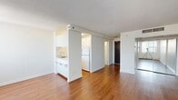 This efficiently designed studio unit in Calgary, AB offers a practical single-floor layout comprising one bedroom, one bathroom, a kitchen, a dedicated entrance, and a combined dining and living area. Throughout the unit, warm-toned hardwood-style flooring adds continuity and a sense of cohesion to the space.

The combined living and dining area serves as the heart of the unit, benefiting from two large windows dressed with vertical blinds that flood the room with natural light. A baseboard heating system runs along the exterior wall, ensuring year-round comfort. The open sightlines and bright white walls contribute to an airy, clean aesthetic.

The kitchen is semi-open to the living area, separated by a partial wall with a pass-through counter. It is equipped with white cabinetry, a sink, and a full-size refrigerator, making efficient use of the available space.

The bedroom is a compact, defined space featuring mirrored sliding closet doors that reflect light and enhance the sense of depth. The entrance offers a dark wood front door and built-in HVAC ventilation overhead. The bathroom includes a vanity with sink. Textured ceilings are consistent throughout, and the overall palette of crisp whites and neutral tones creates a clean, functional living environment well-suited to urban living in downtown Calgary.