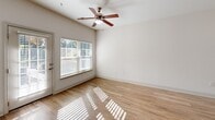 Located at 873 Carmen Way in Rock Hill, South Carolina, this single-story residence combines practical design with a clean, neutral aesthetic throughout. The living areas feature light wood-look flooring that reflects natural light streaming through large windows fitted with blinds, creating a bright and airy atmosphere. Ceiling fans are present in multiple rooms, contributing to both comfort and airflow.

The kitchen is thoughtfully laid out in a galley-style configuration, featuring light wood cabinetry, granite-look countertops, and black appliances including a range, microwave, and a large stainless-steel French door refrigerator. A curved breakfast bar provides additional counter space and casual dining potential, while the double-basin stainless steel sink adds functionality. The kitchen connects conveniently to adjacent spaces via paneled doors.

The bedrooms are finished with plush neutral carpeting and include generous closet storage, with at least one room featuring double doors for expanded capacity. Natural light enters through multi-pane windows, enhancing the sense of space.

The bathroom is designed with accessibility in mind, equipped with multiple brushed nickel grab bars around a tub-shower combination, a handheld showerhead, and wood-look flooring that ties back to the rest of the home. The overall ambiance throughout is clean, neutral, and move-in ready.