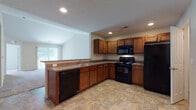 Located at 1802 Kelly's Path in Reynoldsburg, Ohio, this single-floor home offers a practical and well-organized layout designed for comfortable everyday living. The open-concept kitchen is a central highlight, featuring warm medium-toned wood cabinetry, dark granite-style countertops, stone-look tile flooring, and a full suite of black appliances including a refrigerator, electric range, over-the-range microwave, and dishwasher. A peninsula with a sink provides additional workspace and connects seamlessly to the adjacent living area, which benefits from natural light through vertical blinds. The bedrooms are finished with neutral-toned carpet and feature windows that allow natural light to fill each room. The home includes two bathrooms: a full bathroom with a soaking tub, tile flooring, and a single-sink vanity with wood cabinetry, and a second bathroom featuring a standalone glass-door shower, tile flooring, and a matching vanity. The textured ceilings and recessed lighting throughout add to the clean, consistent aesthetic of the interior. Completing the home is a spacious attached two-car garage equipped with an automatic opener, offering generous storage and parking capacity.