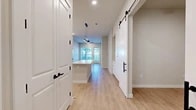 Located along IH-30 E in Fort Worth, TX, this well-designed 2-bedroom, 2-bathroom unit offers a thoughtfully laid-out single-floor plan with modern finishes throughout. Light wood-tone flooring flows seamlessly across the entire space, complementing the neutral wall palette and creating a warm, cohesive ambiance.

The open-concept kitchen and living area serves as the heart of the unit. The kitchen is a standout, featuring a striking two-tone design with navy lower cabinets and crisp white upper cabinetry, a herringbone tile backsplash, quartz countertops, stainless steel appliances, and a central island for additional prep and seating space. A decorative sliding barn door adds a stylish architectural accent to the main corridor.

The living area benefits from generous natural light, with large windows and a glass door opening to an outdoor view of mature trees, creating a bright and inviting atmosphere.

The primary bedroom is a comfortable retreat with a dedicated walk-in closet and an en-suite bathroom complete with a soaking tub, tiled surround, and white vanity with matte black hardware. The second bedroom also enjoys natural light through a well-positioned window. A second full bathroom with gold-accented cabinetry provides additional convenience. With five closets total, storage is plentiful throughout.