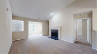 This well-appointed single-story home in Charlotte, NC offers a thoughtful layout across three bedrooms and two full bathrooms. The living room immediately impresses with vaulted ceilings, plush carpeting, and a classic wood-burning fireplace with a white-painted mantle and slate hearth. Built-in shelving flanks one wall, adding both character and function, while multiple windows invite generous natural light throughout the space. The open-concept design connects the living area seamlessly to a dedicated dining space and kitchen. The kitchen features rich dark cabinetry, granite countertops, a tile backsplash, stainless steel appliances, and a peninsula that serves as both a prep area and casual dining bar. Each bedroom is carpeted and well-proportioned, with the spacious primary bedroom offering ample room and natural light. The two bathrooms are finished with dark wood vanities, granite countertops, large mirrors, and wood-look flooring. One bathroom includes a full tub-shower combination with tiled surround. A dedicated laundry room with wood-look flooring, wire shelving, and space for full-size washer and dryer adds everyday convenience. The home's neutral palette and consistent finishes create a cohesive, move-in-ready living environment.