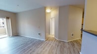 Located at 1203 Carson Ln SE in Lacey, Washington, this single-floor unit presents a clean, modern interior with a cohesive design throughout. The entryway opens into a bright, open living area finished with light wood-style luxury vinyl plank flooring and neutral gray walls, creating a welcoming and versatile space. A sliding door allows natural light to fill the living area, adding to its airy feel. The galley-style kitchen is efficiently laid out and features warm wood-toned cabinetry, dark countertops, a stainless steel refrigerator, stainless steel range, and built-in microwave, offering a well-equipped cooking space. A pantry door provides additional storage convenience. The bedroom is carpeted in warm tones and includes a large window with blinds that invites natural light, along with a baseboard heating unit. The bathroom is accessible from the bedroom area and includes warm wood-toned cabinetry with a single sink, dark countertop, mirrored medicine cabinets with vanity lighting, and light tile flooring. A walk-in closet adjacent to the bathroom provides generous storage. Throughout the unit, white trim and panel doors add a crisp, finished look, while wall-mounted heating units ensure year-round comfort.